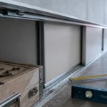poser une porte de placard coulissante : rails alignés, mètre et niveau